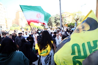 A protestor carries an Iranian flag, and wears a Hezbollah shawl.