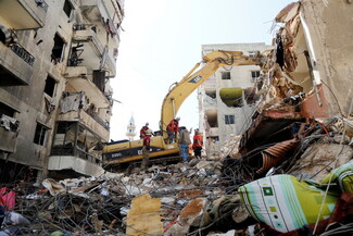 Rescue workers and excavator amid the rubble of partially collapsed buildings in Dahieh, Beirut after an Israeli strike.