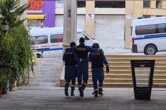 Three medics in blue uniforms support each other as they walk away from ambulances.