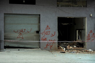 Damaged building with graffiti reading "Do not approach" in Arabic.