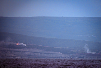 Two locations in distant hills where smoke is rising, appearing to be sites of bombing.