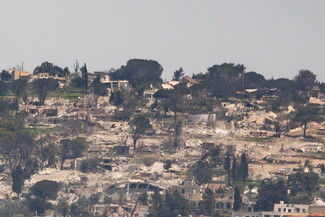 Lebanese village with scattered, damaged and destroyed buildings, rubble, and sparse trees.