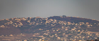 Hilly landscape dotted with numerous white buildings showing a village in south Lebanon.