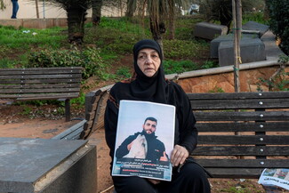 A Veiled woman holds the photo of her son while sitting on a bench in a park in Beirut. 