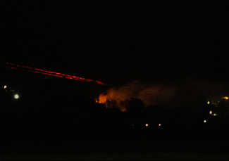A nighttime scene with smoke rising in the distance.