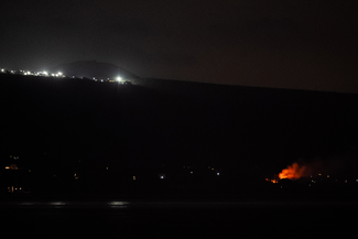 A nighttime scene with smoke rising in the distance.