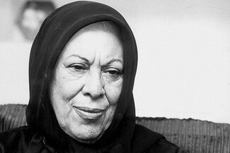 A close-up black-and-white portrait of author Simin Daneshvar, wearing a dark headscarf. She looks slightly downward and to the side with a gentle, serene expression.