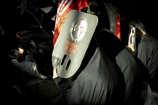 A crowd of mourners at a funeral hold up a sign that depicts Israeli Prime Minister Benjamin Netanyahu with a sniper target on his face, and written in English and Farsi is: "THERE WILL BE BLOOD."