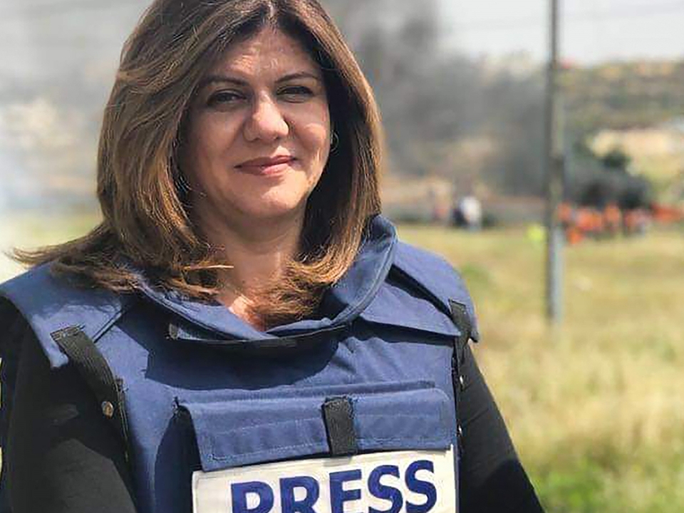 Beloved journalist and martyr Shireen Abu Akleh smiling at the camera, wearing a blue press vest.
