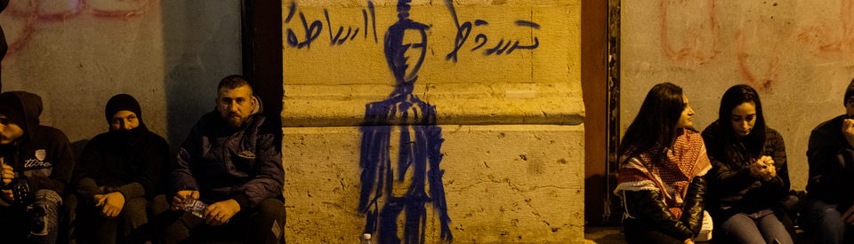 متظاهرون يرتاحون قرب رسم يظهر فيه مشنوقا شخصا يمثّل السلطة. وسط بيروت، لبنان. ١٥ كانون الأول ٢٠١٩. (ريتا قبلان، مصدر عام)