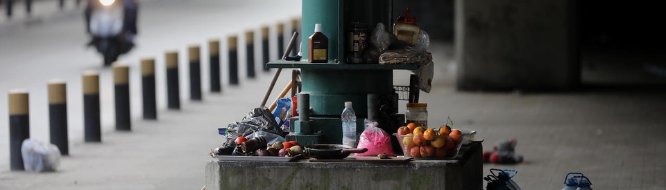 Bruised fruits and kitchen utensils are laid around the green metal column of the Fiat bridge in Beirut.