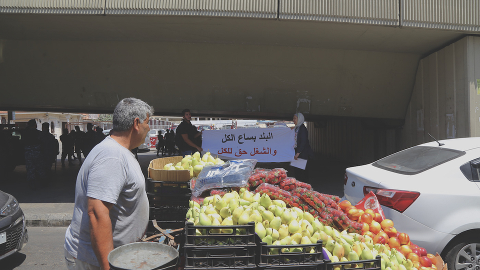 A street cart vendor passes by a protest near the Lebanese Ministry of Labor in Beirut against the crackdown on unregulated labor, July 30, 2019. (Hussein Baydoun/The Public Source)