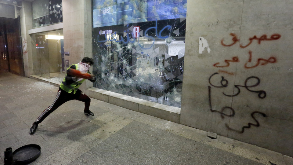 متظاهر يحطّم واجهة مصرف في شارع الحمرا في بيروت في إطار "أسبوع الغضب" احتجاجا على تدهور الوضع الاقتصادي. ١٥ كانون الثاني ٢٠١٩. (مروان طحطح، مصدر عام)