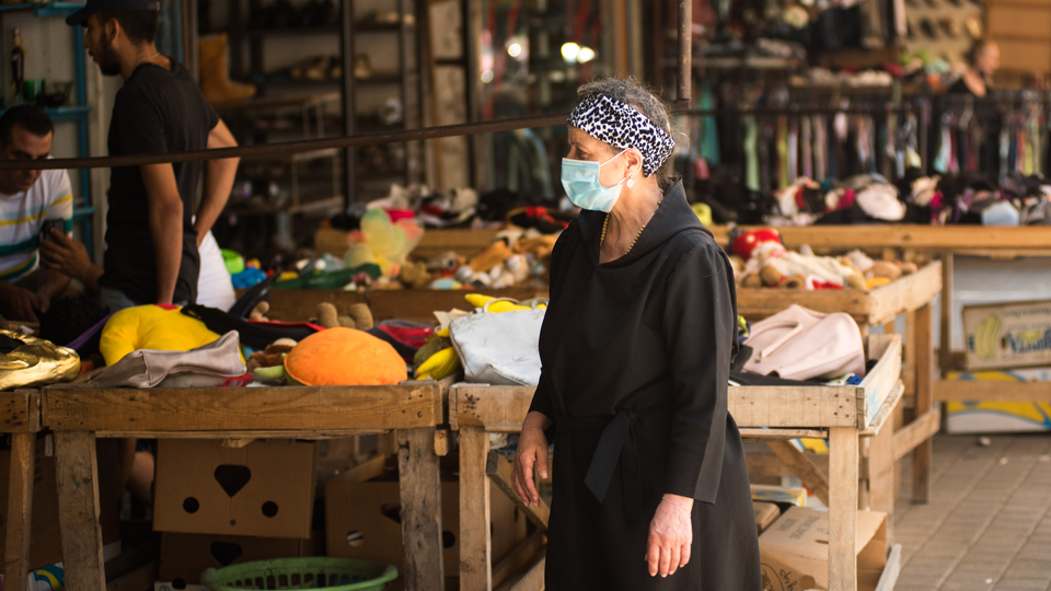 A woman donning a mask makes her way through a secondhand market in Tripoli near Nahr Abu Ali. Tripoli, Lebanon. June 13, 2020. (Natheer Halawani/The Public Source)