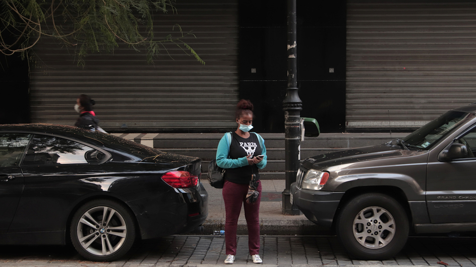 امرأة تنتظر سيارة أجرة في شارع الحمرا المغلق. بيروت، لبنان. ٢٧ تشرين الثاني، ٢٠٢٠. (فاطمة فؤاد، مصدر عام)