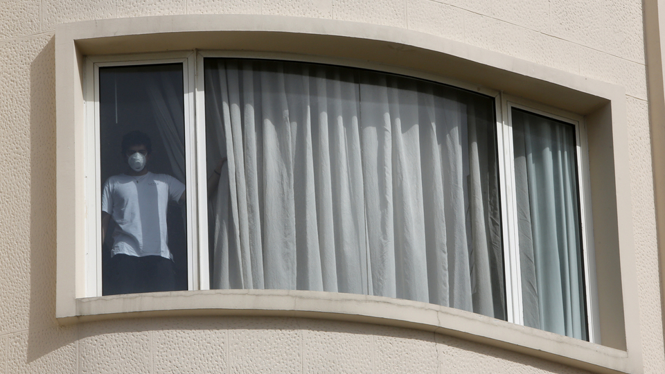A man wearing a mask stands at the window of his apartment. Beirut, Lebanon. May 2020. (Marwan Tahtah/The Public Source)