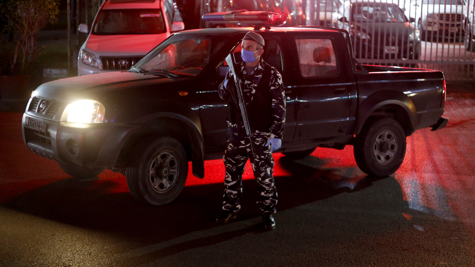 ضابط في الشرطة يقف أمام سيارة دوريّة ليلًا. جلّ الديب، لبنان. نيسان ٢٠٢٠. (مروان طحطح ، مصدر عام)
