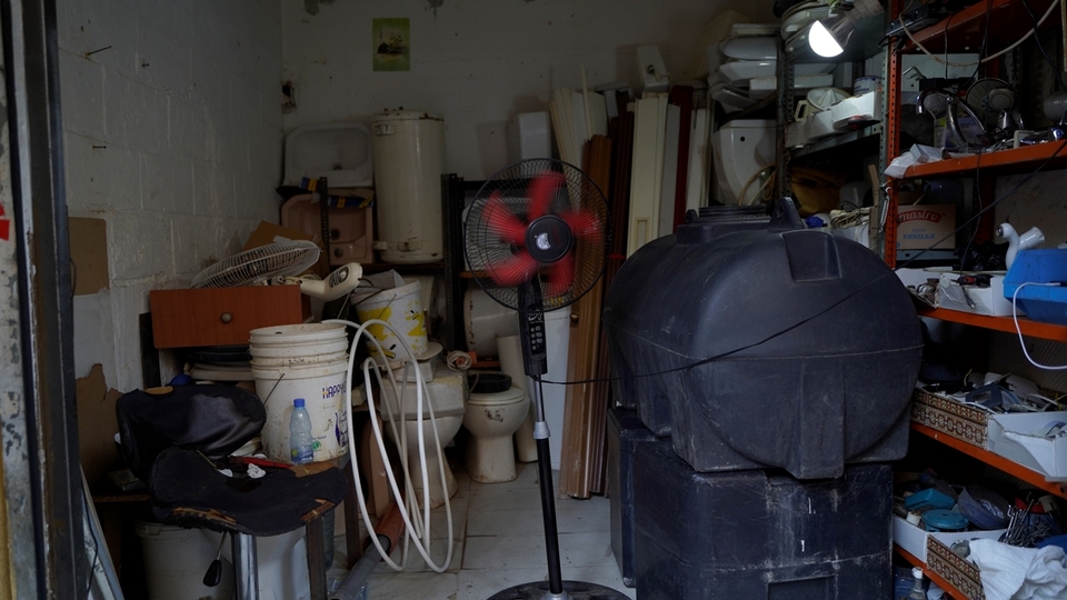 A plumber has set up shop for repairs and used appliances. He  buys and resells all types of refurbished items, such as fans, toilet seats, office chairs, heaters, water tanks, and faucets. Nabaa, Lebanon. June 26, 2021. (Mohamad Cheblak / The Public Source)