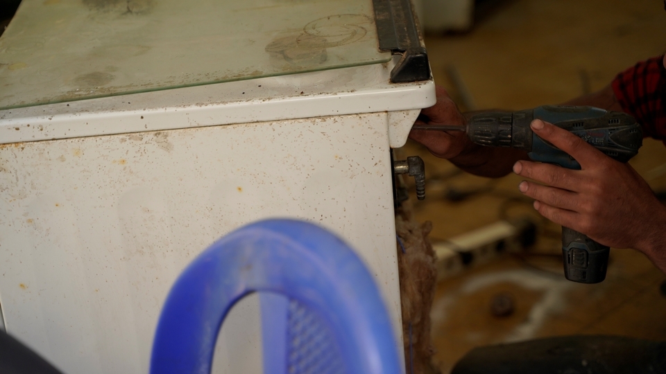 A worker repairs a used stove top to resell in his shop. He lost his job as a concrete pump truck driver a year and a half ago, and has taken up repair work since. At best, he makes 50,000 L.L. per item sold, and cannot count on a daily income because the business is not stable. Nabaa, Lebanon. June 26, 2021. (Mohamad Cheblak/The Public Source)