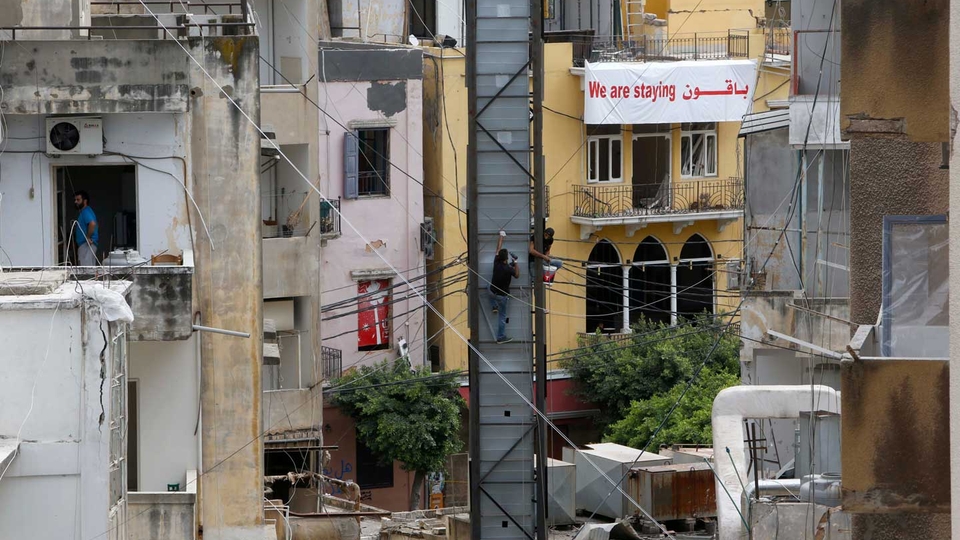 لافتة كتب عليها " باقون"، تتدلّى من شرفة بناية مدمّرة في منطقة مار مخايل. آب ٢٠٢٠. (مروان طحطح/مصدر عام)