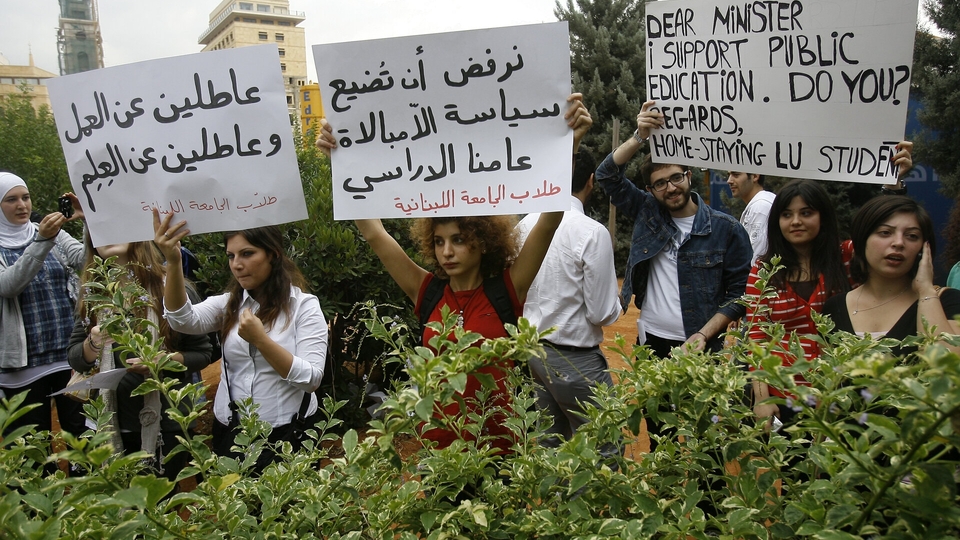 Lebanese University students holding cardboard signs join a protest in solidarity with their professors' strike.