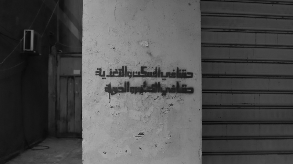 “Our right to housing and sustenance, our right to education and freedom” is written on the wall of a building.