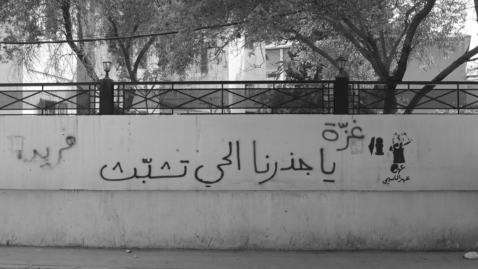 “Ahed Al-Tamimi” is stenciled on a wall next to “Gaza, our living root, hang on”.