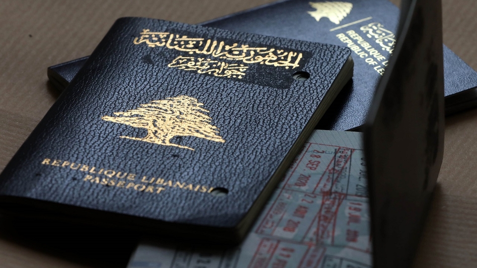 Three Lebanese passports; two are closed, displaying their covers; one is open displaying travel stamps.