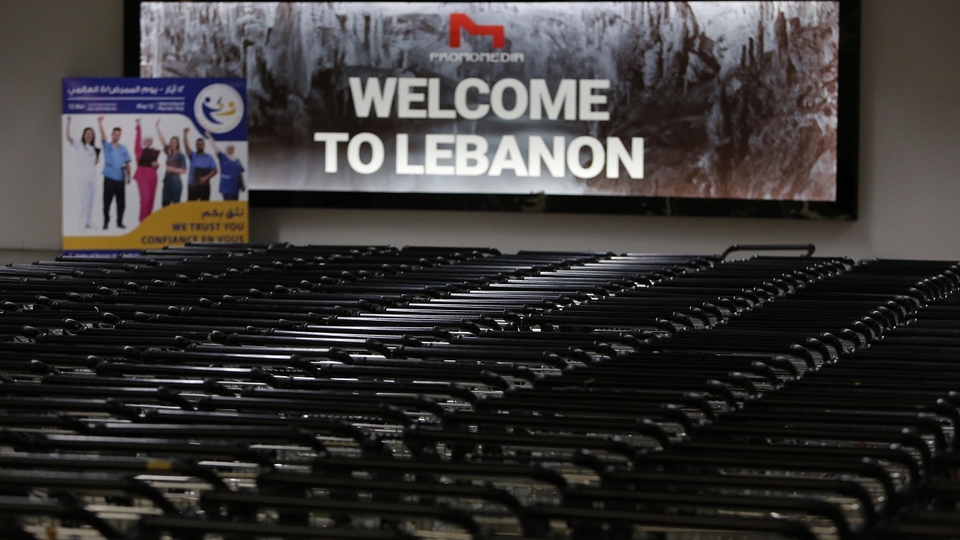 Stack of trollies in front of a sign that reads “Welcome to Lebanon”  at the Beirut International Airport.