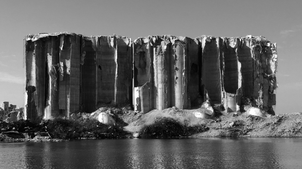 Black and white view from the sea of the destroyed silos.