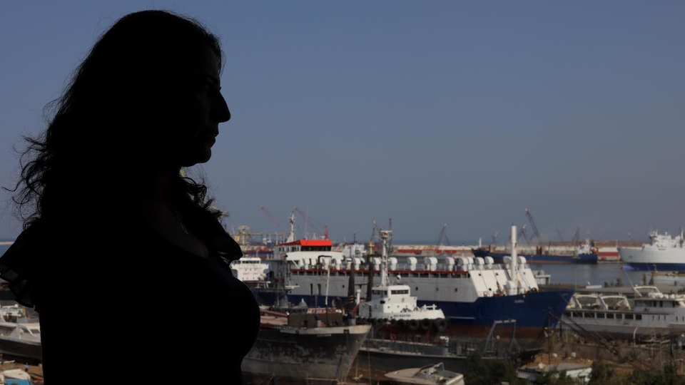 Silhouette of a woman looking over Tripoli's seaport