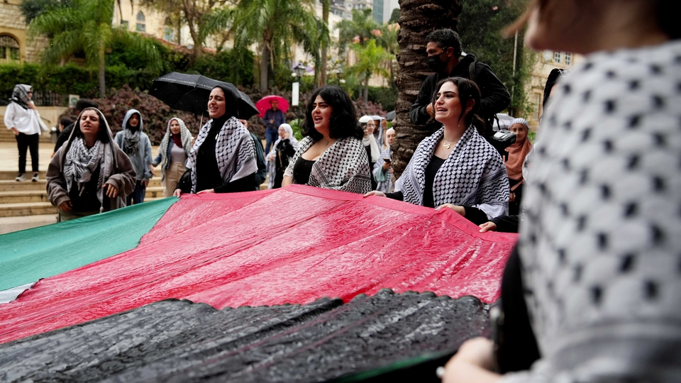 Student protesters hold a large Palestinian flag